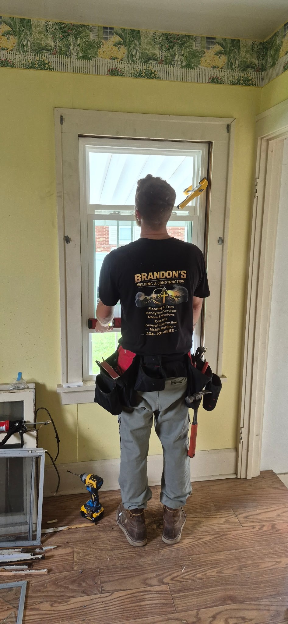 Worker standing beside a newly installed replacement window inside a home